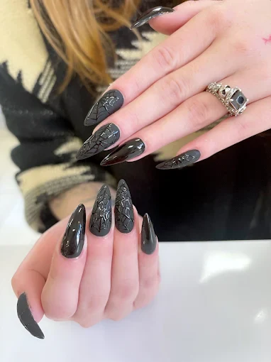 Glossy black stiletto nails with raised lace texture by Top 10 Nails Spa
