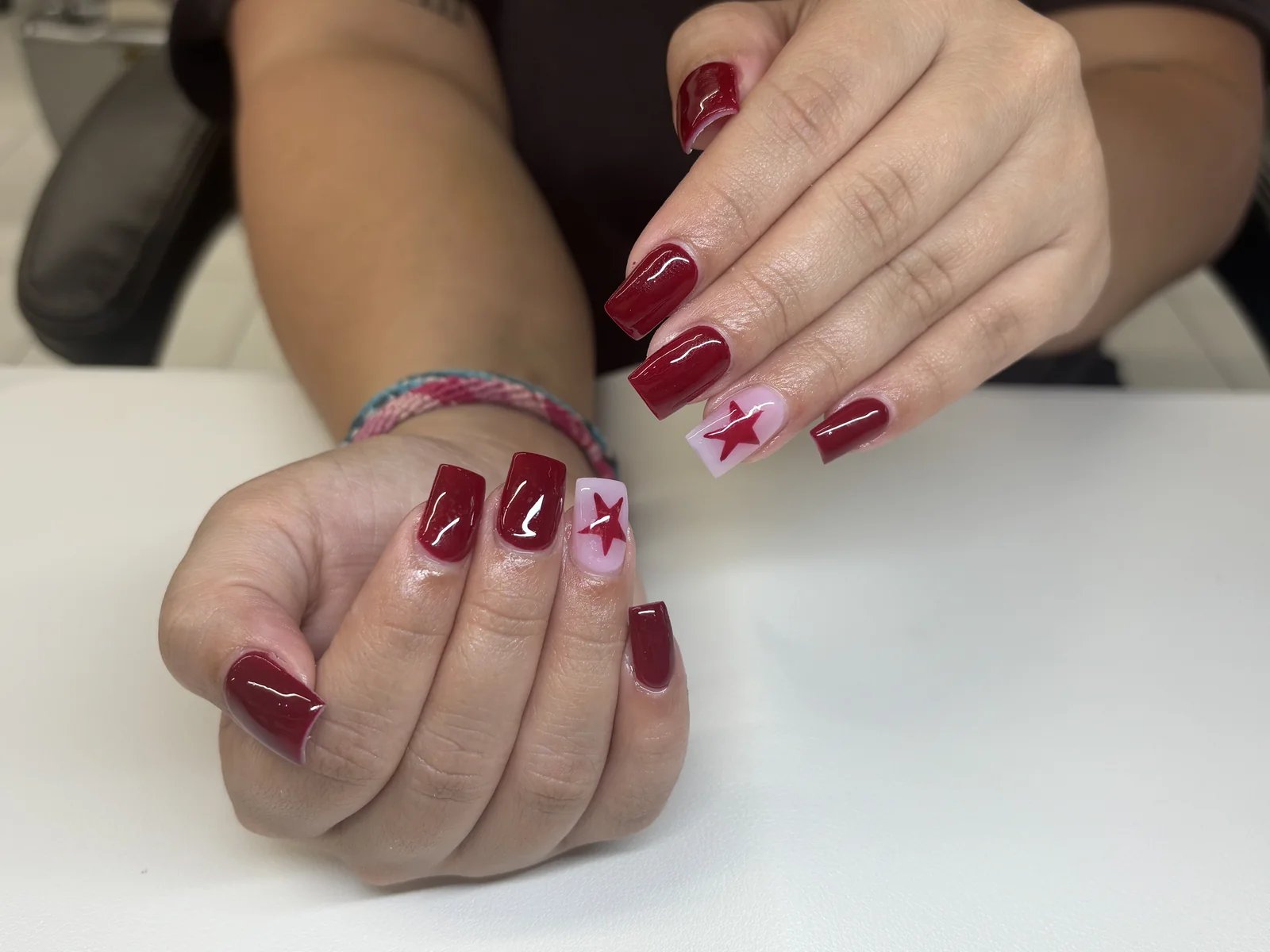 Cherry red nails with white star accents by Top Ten Nails Spa